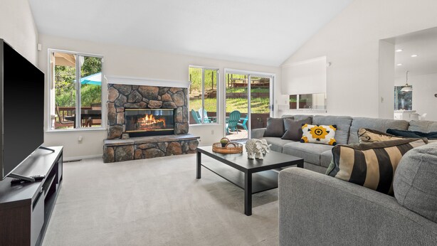 A modern living room with a stone fireplace, a grey sofa, and a flat-screen TV. - Between Napa & San Francisco 6bed 4bath Clean (Concord)