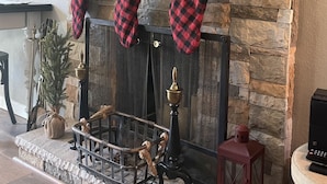 Una chimenea con tres calcetines rojos y negros a cuadros colgados encima.