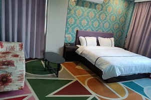 Habitación de hotel con cama, una silla, una mesita y pared con diseño.