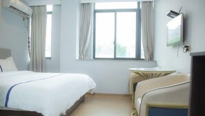 A hotel room with a bed, a small table, a TV, and a window with curtains. - edinburgh hotel (Haining)