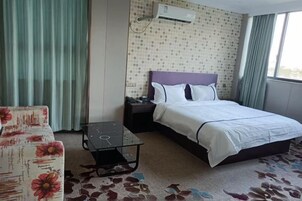 Una habitación de hotel con una cama, una mesita de noche, una silla, una pequeña mesa y una ventana con cortinas.