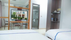 A hotel room with a bed, a desk with a chair, a glass door leading to a shower, and a shelf with items. - edinburgh hotel (Haining)