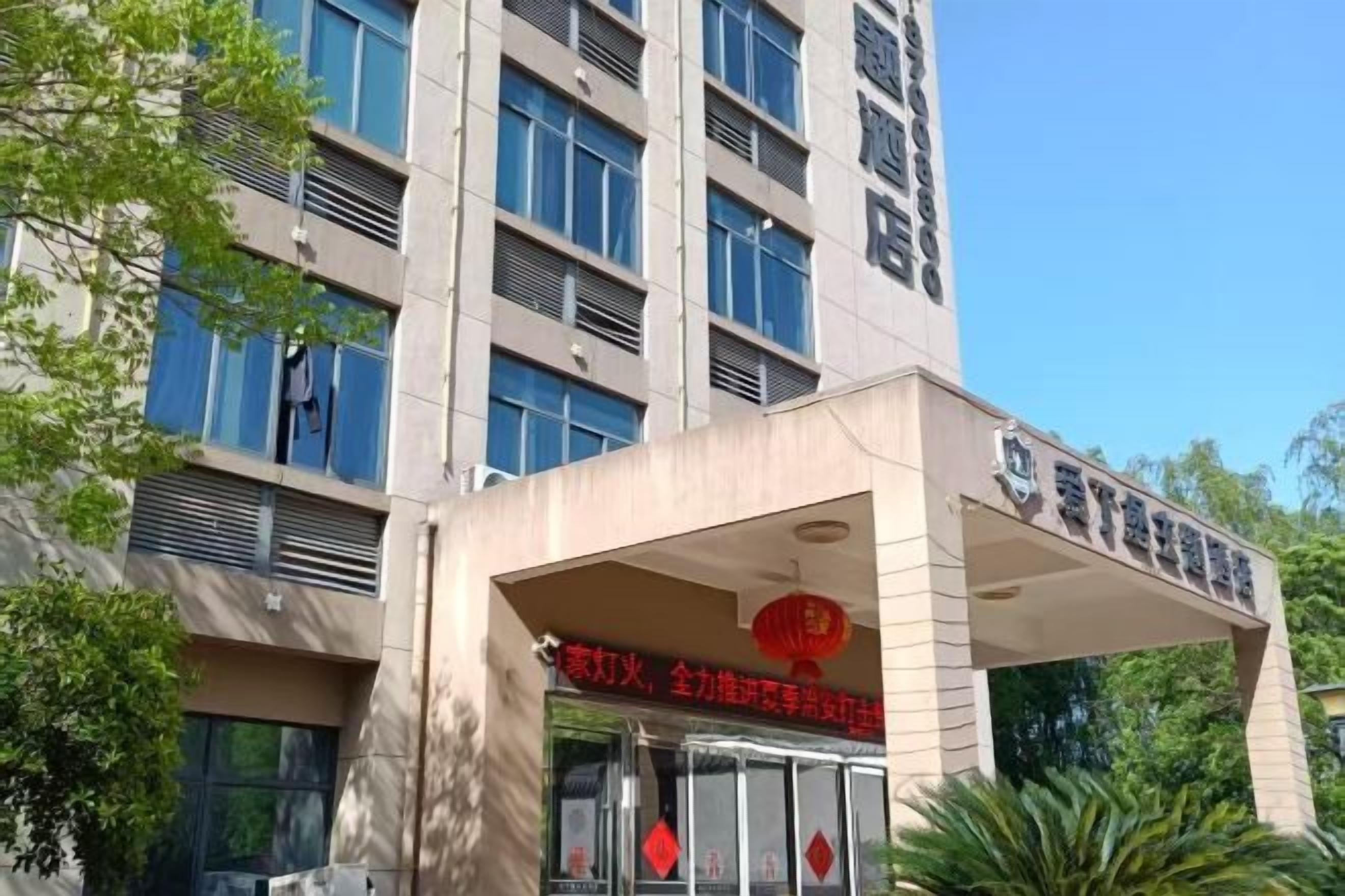 Een gebouw met een opvallende ingang, grote ramen en een bord met Chinese karakters.