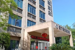 Een gebouw met een opvallende ingang, grote ramen en een bord met Chinese karakters.
