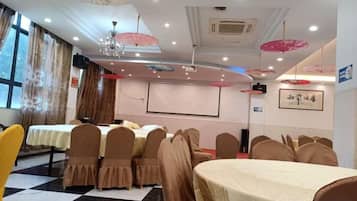 A conference room with tables and chairs, a projector screen, and a large window.