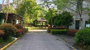 A pathway leading to a gazebo surrounded by lush greenery and a building. - edinburgh hotel (Haining)