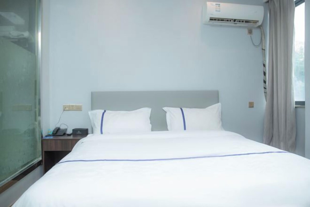 Une chambre d’hôtel équipée d’un lit, d’une table de chevet, d’un téléphone et d’un appareil de climatisation.