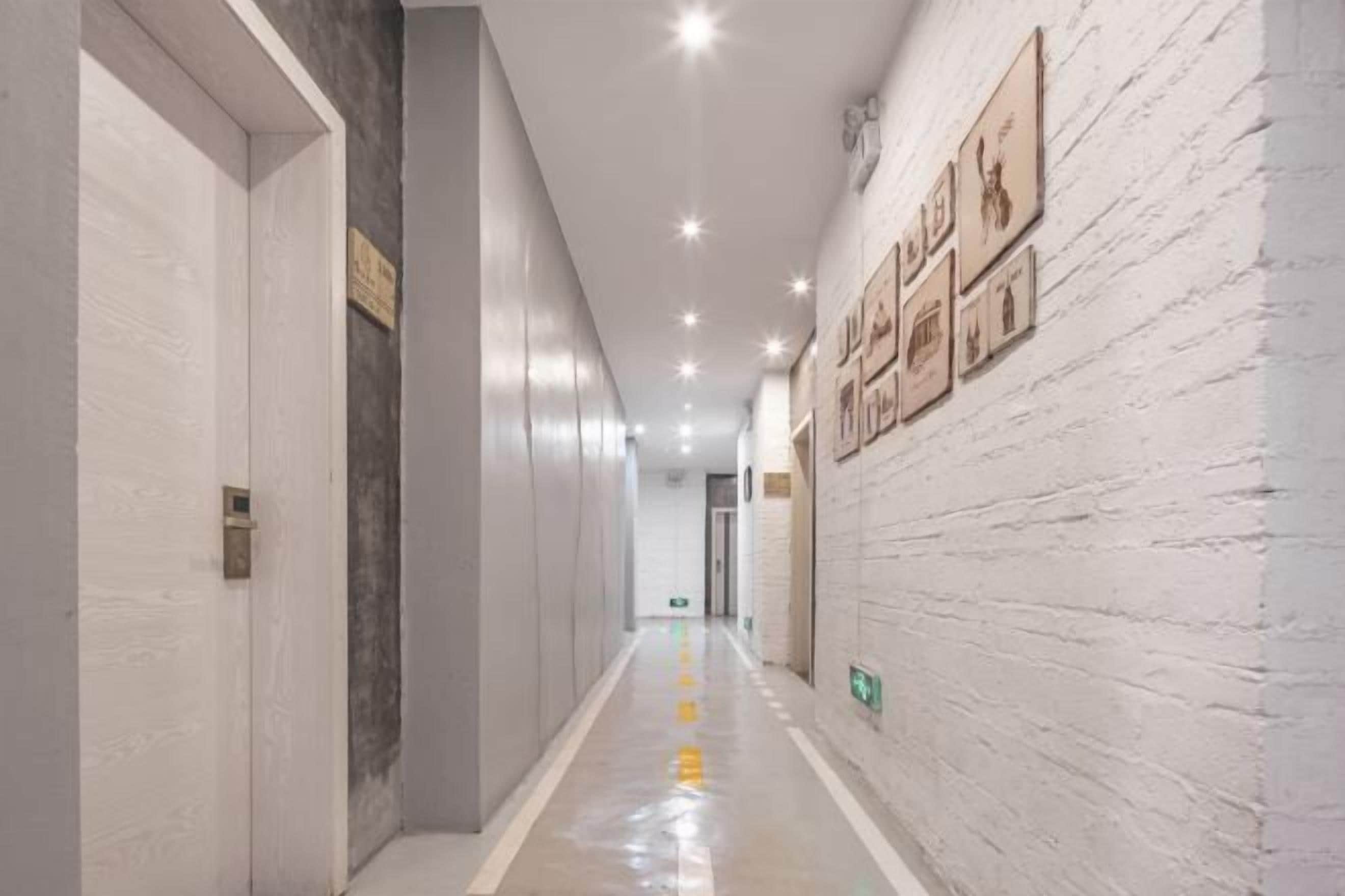A hallway with white brick walls, framed pictures, and a reflective floor.