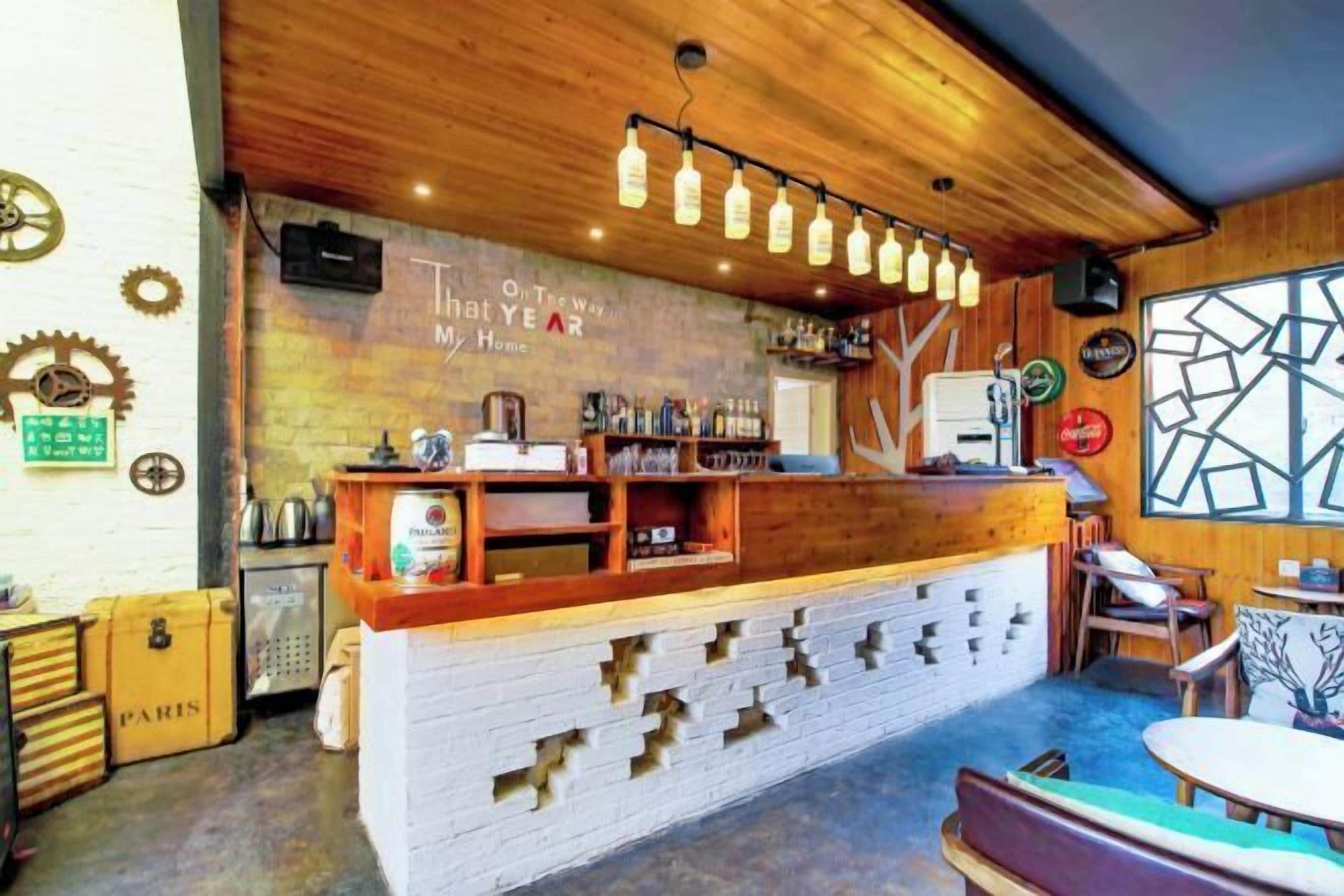 A bar area with a wooden counter, shelves with bottles, and a sign that reads "On The Way My Home."