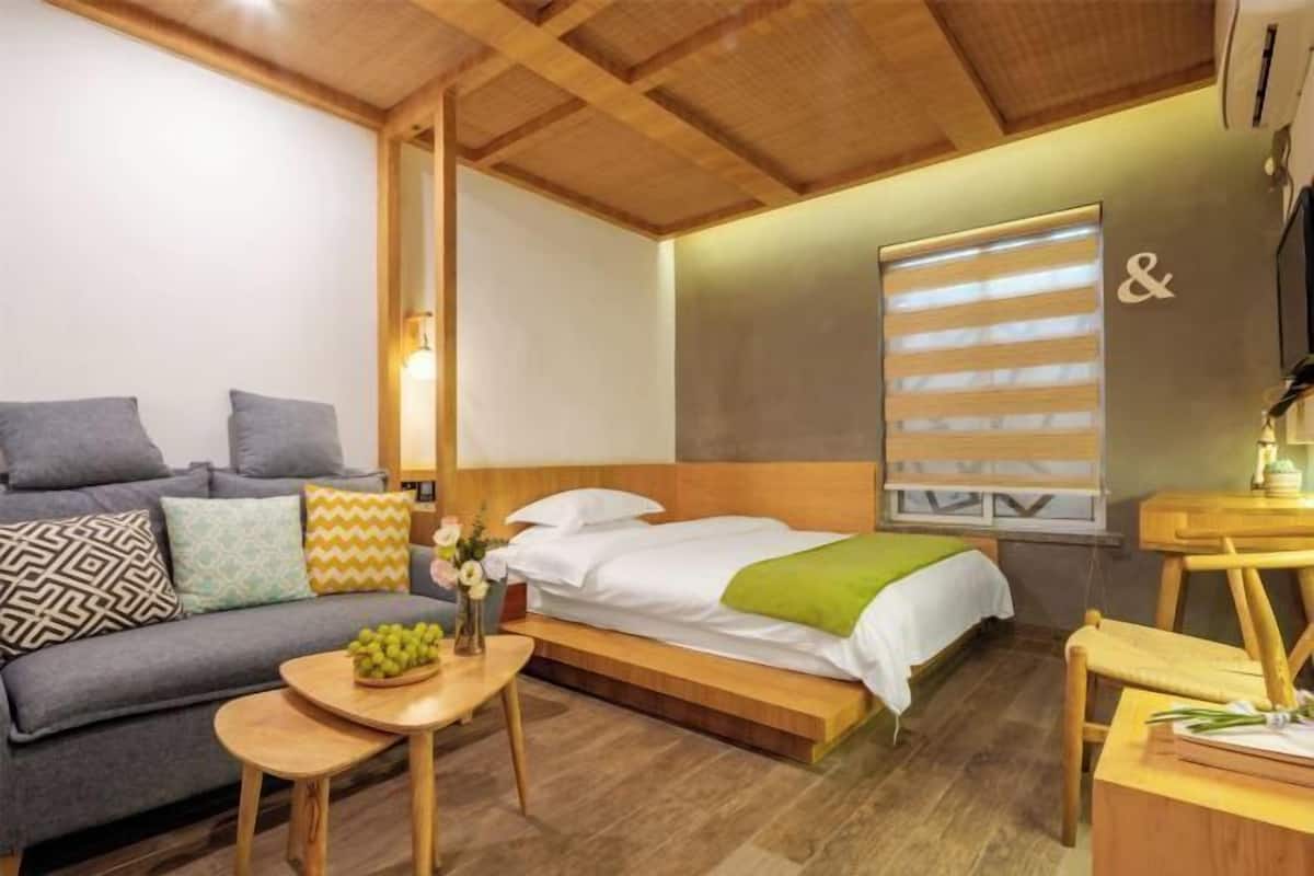 A modern hotel room with a bed, a sofa, a small table, and a desk.