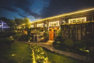 A well-lit hotel with a prominent entrance, a garden area with a pathway, and a large windowed section.
