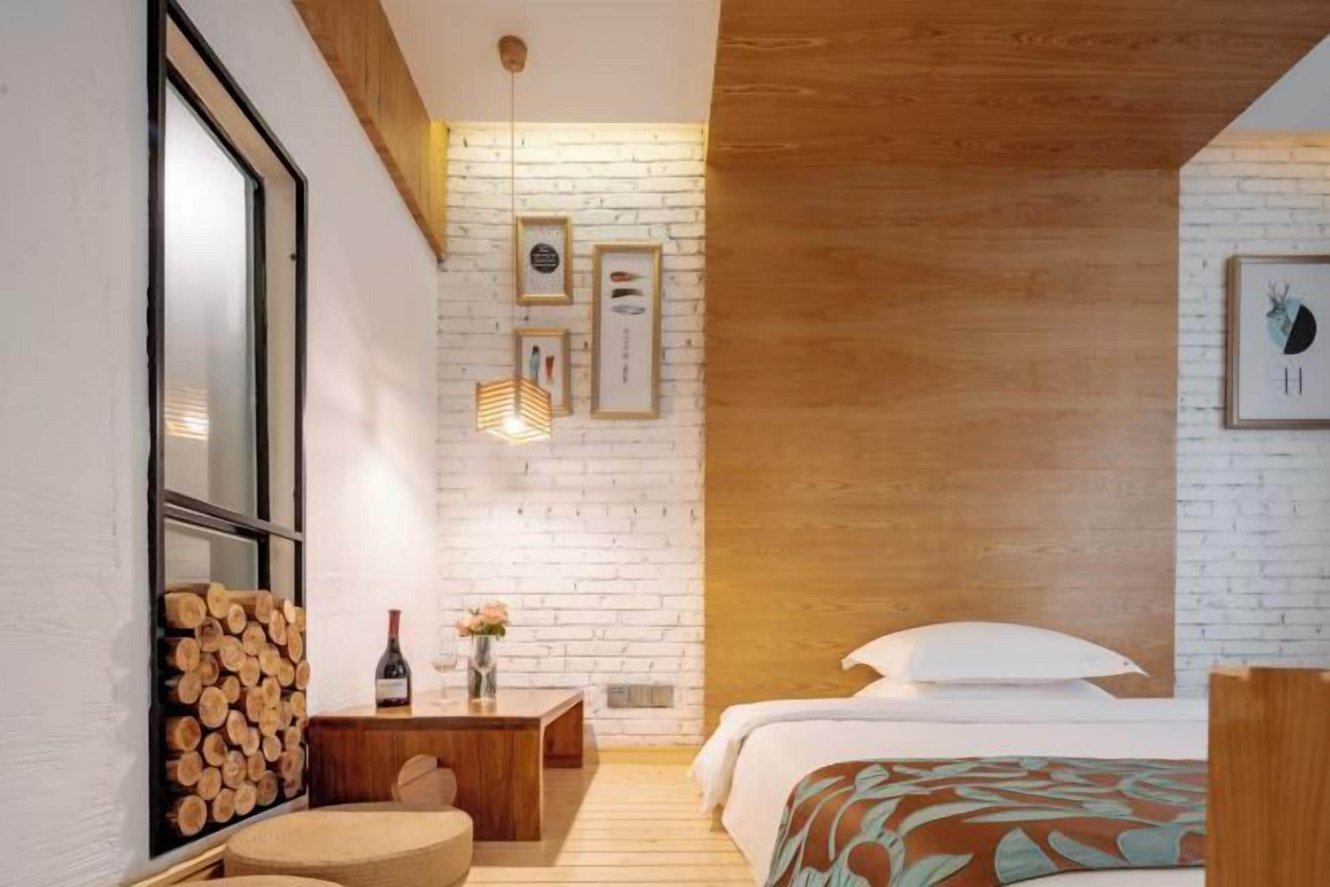 Un dormitorio moderno con techo de madera, una cama con ropa blanca, una mesita de noche de madera y un marco de fotos colgado en la pared.