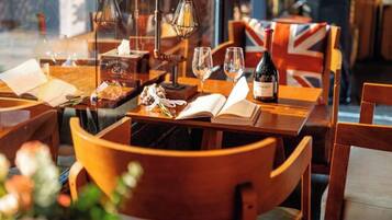 A restaurant setting with wooden tables, chairs, and a bottle of wine.