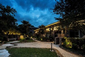 A well-lit outdoor area with a pathway leading to a building, surrounded by greenery and trees. - That Year Boutique Theme Inn (Zixing)
