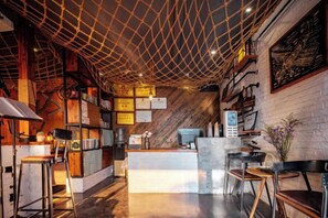 Interior de restaurante con techo de madera, zona de bar, asientos y barra.