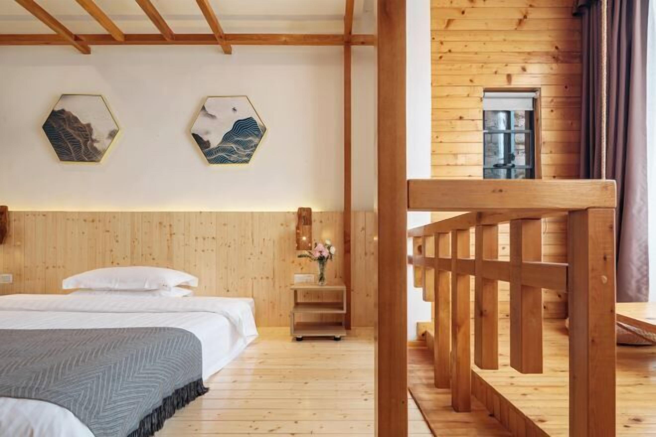 Interior de una cabaña de madera con una cama, paredes de madera y una obra de arte hexagonal en la pared.
