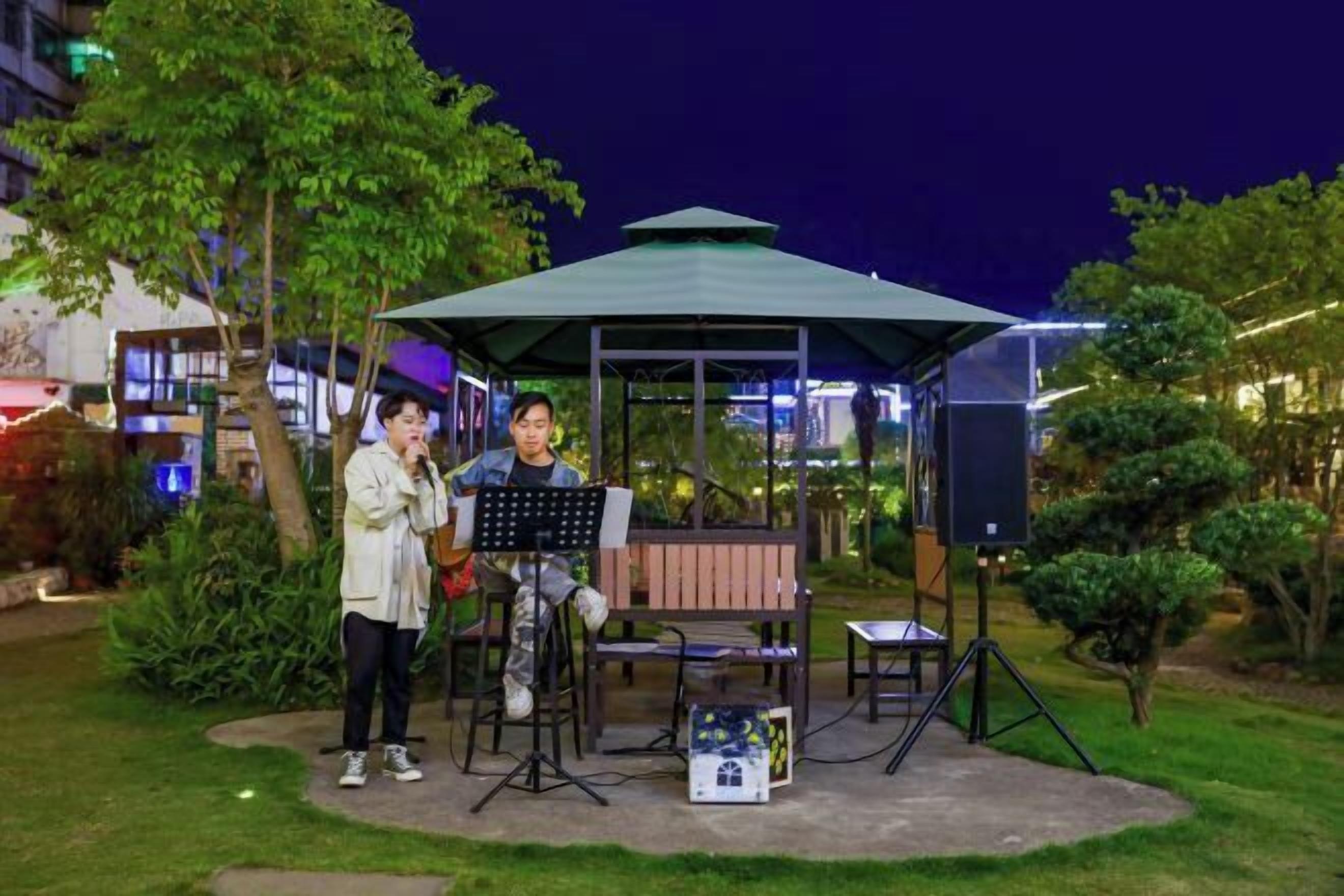 Un pabellón con un músico y un cantante actuando al aire libre de noche.