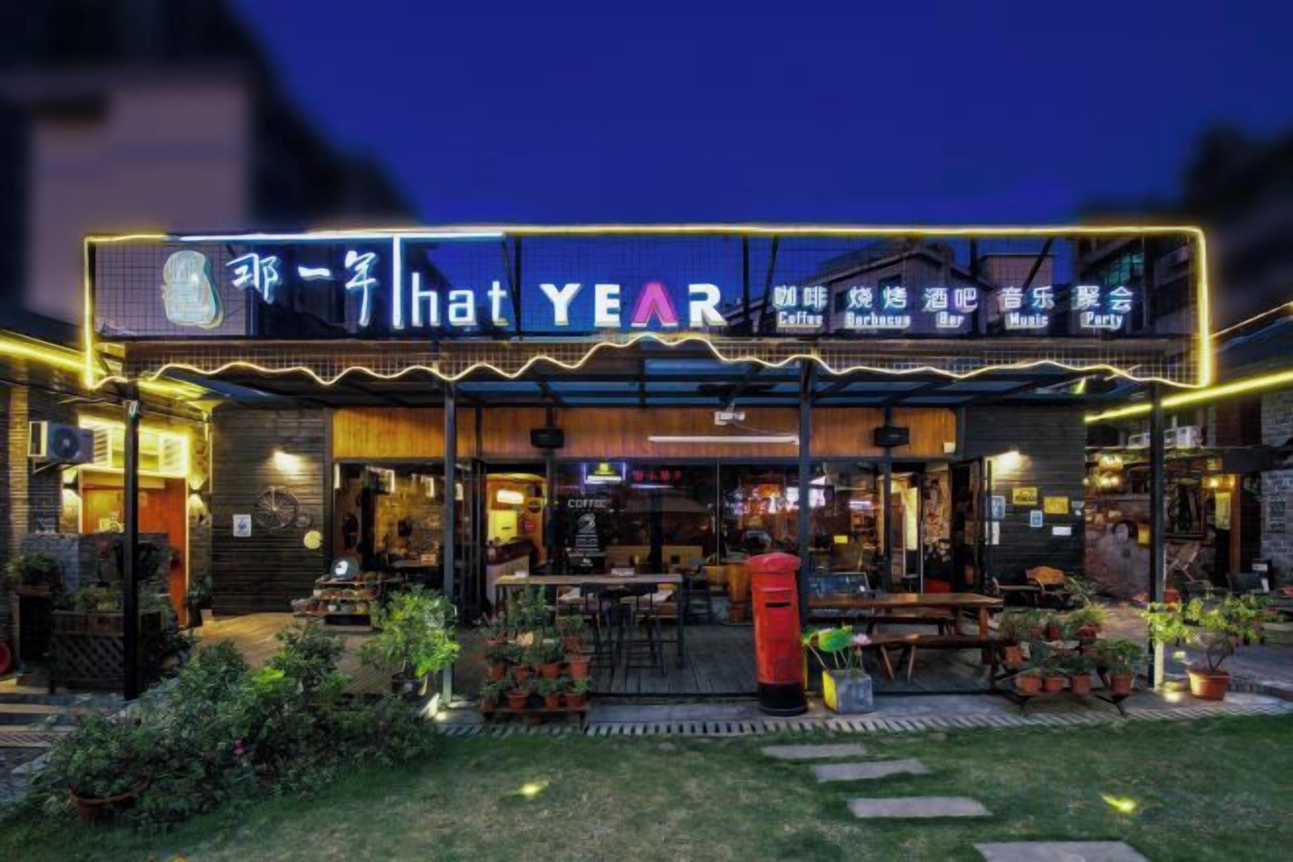 Un restaurant avec une terrasse et un panneau lumineux au néon.