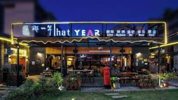 Un restaurant avec une terrasse et un panneau lumineux au néon.