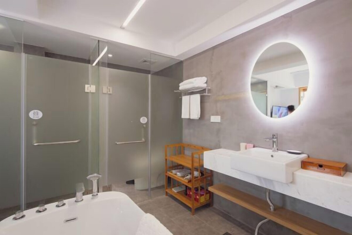 A modern bathroom with a large bathtub, a vanity with a mirror, and a wooden shelf.