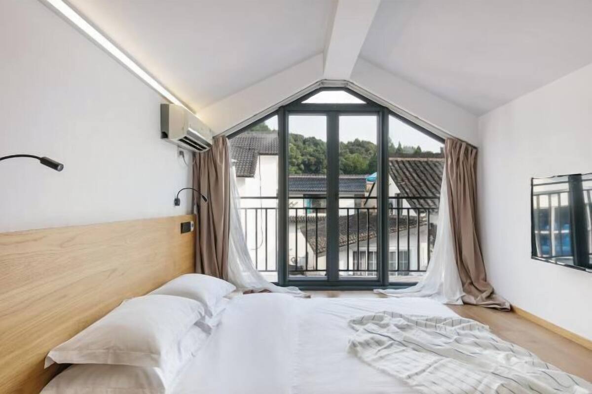 Ein Schlafzimmer mit einem Bett, einem Fenster und Blick auf ein Gebäude.