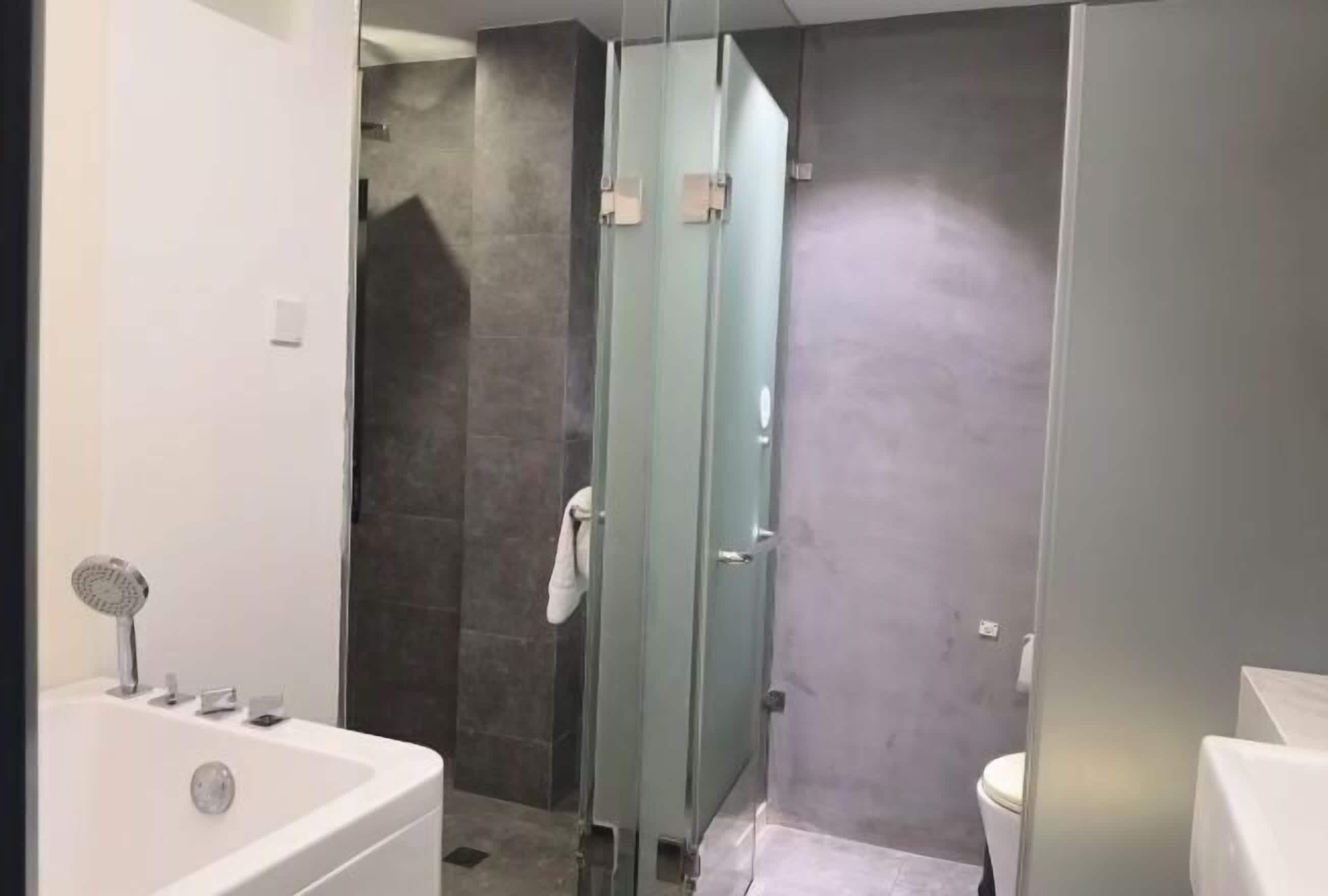 A bathroom with a bathtub, a glass shower enclosure, and a toilet.