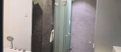 A bathroom with a bathtub, a glass shower enclosure, and a toilet.