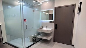 Un bagno moderno con cabina doccia in vetro, un mobile lavabo con specchio e una porta.