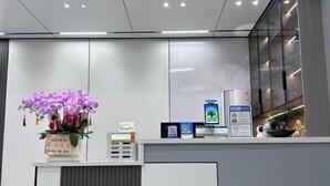 Una reception con un vaso di fiori viola, un chiosco digitale e manifesti informativi.