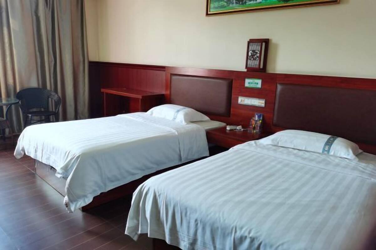 Une chambre d’hôtel avec deux lits, un bureau, une chaise et un tableau accroché au mur.