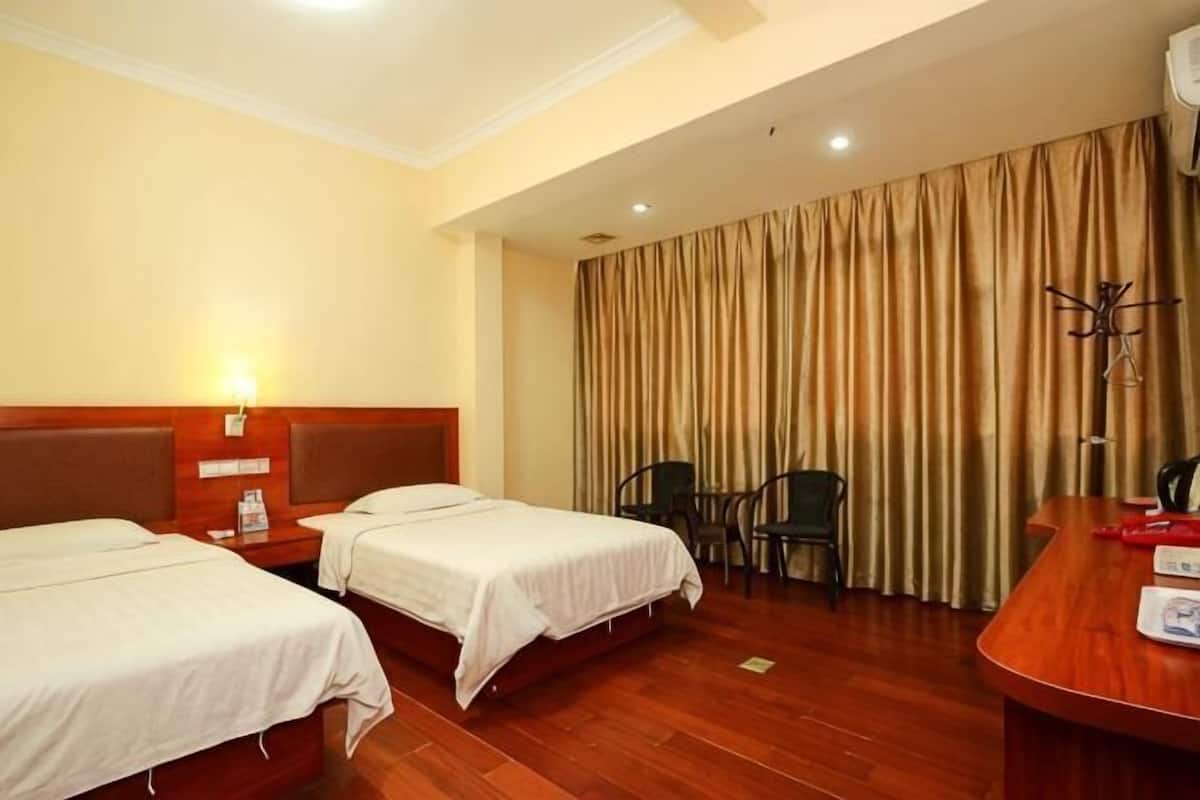 Une chambre d’hôtel avec deux lits, un bureau, une chaise et un rideau.