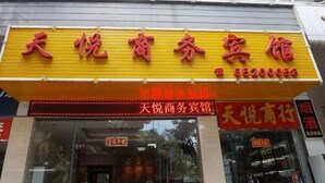 A hotel with a yellow signboard displaying the name and contact number. - Tianyue Business Hotel (Haikou)