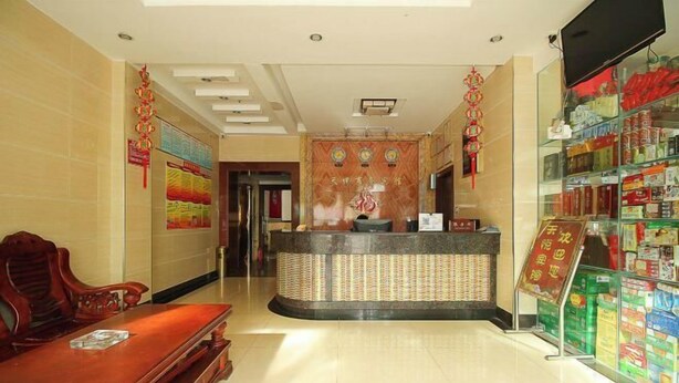 A hotel lobby with a reception desk, seating area, and a display of products. - Tianyue Business Hotel (Haikou)