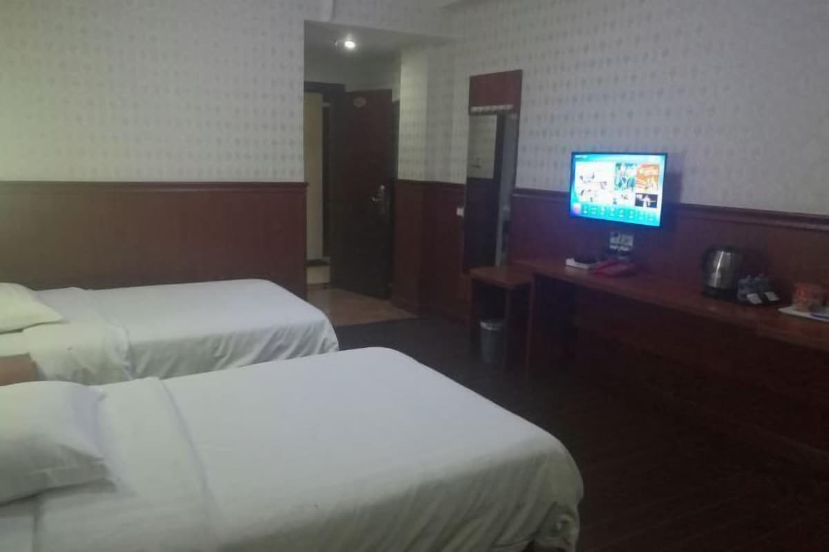 A hotel room with two beds, a desk with a computer, and a mirror.