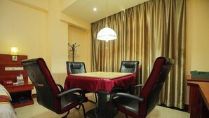 A hotel room with a dining table, four chairs, a lamp, a coat rack, and a curtain. - Tianyue Business Hotel (Haikou)