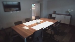 A dining area with a long wooden table, black chairs, and a white table runner. There is a small decorative item on the table.