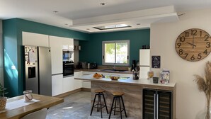 Een moderne keuken met blauwgroene muren, een grote klok en een eethoek met krukken.