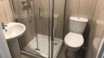 Een douche, handdoeken, zeep, toiletpapier