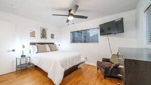 Une chambre à coucher comprenant un lit, un bureau, une chaise, un téléviseur et un ventilateur de plafond.