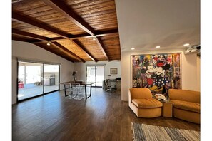 Relax in this stylish living area with a high ceiling, modern sofa, and vibrant mural.