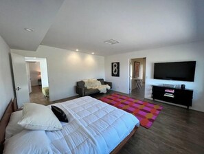 Een moderne slaapkamer met een groot bed, een televisie en een zithoekje.