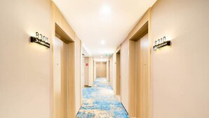 A hotel hallway with a blue and beige carpet, numbered doors, and a light ceiling. - Pujiang Qianbaidu Hotel (Pujiang)