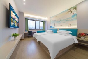 Habitación de hotel con una cama grande, un escritorio, un televisor montado en la pared y un cuadro con una playa.