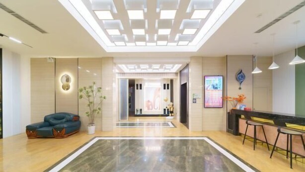 A spacious lobby with a modern design, featuring a large reception desk, seating area, and a decorative ceiling. - Pujiang Qianbaidu Hotel (Pujiang)