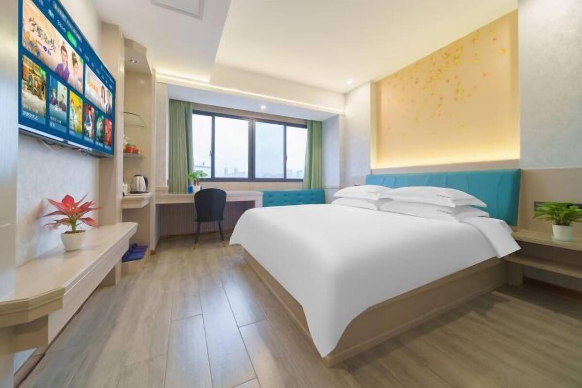 A modern hotel room with a large bed, a desk, and a window.