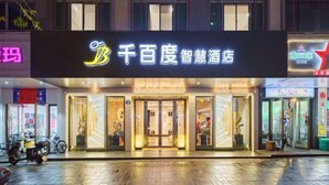 A hotel entrance with a neon sign, glass doors, and a well-lit interior. - Pujiang Qianbaidu Hotel (Pujiang)