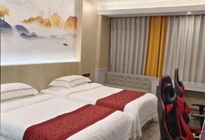Habitación de hotel con dos camas, un cuadro grande en la pared, vistas a las montañas y un escritorio con una silla.
