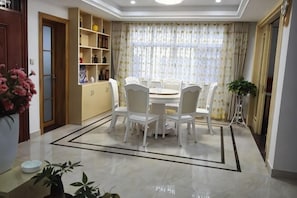 Un coin repas avec une table ronde et des chaises, une bibliothèque et une plante en pot.
