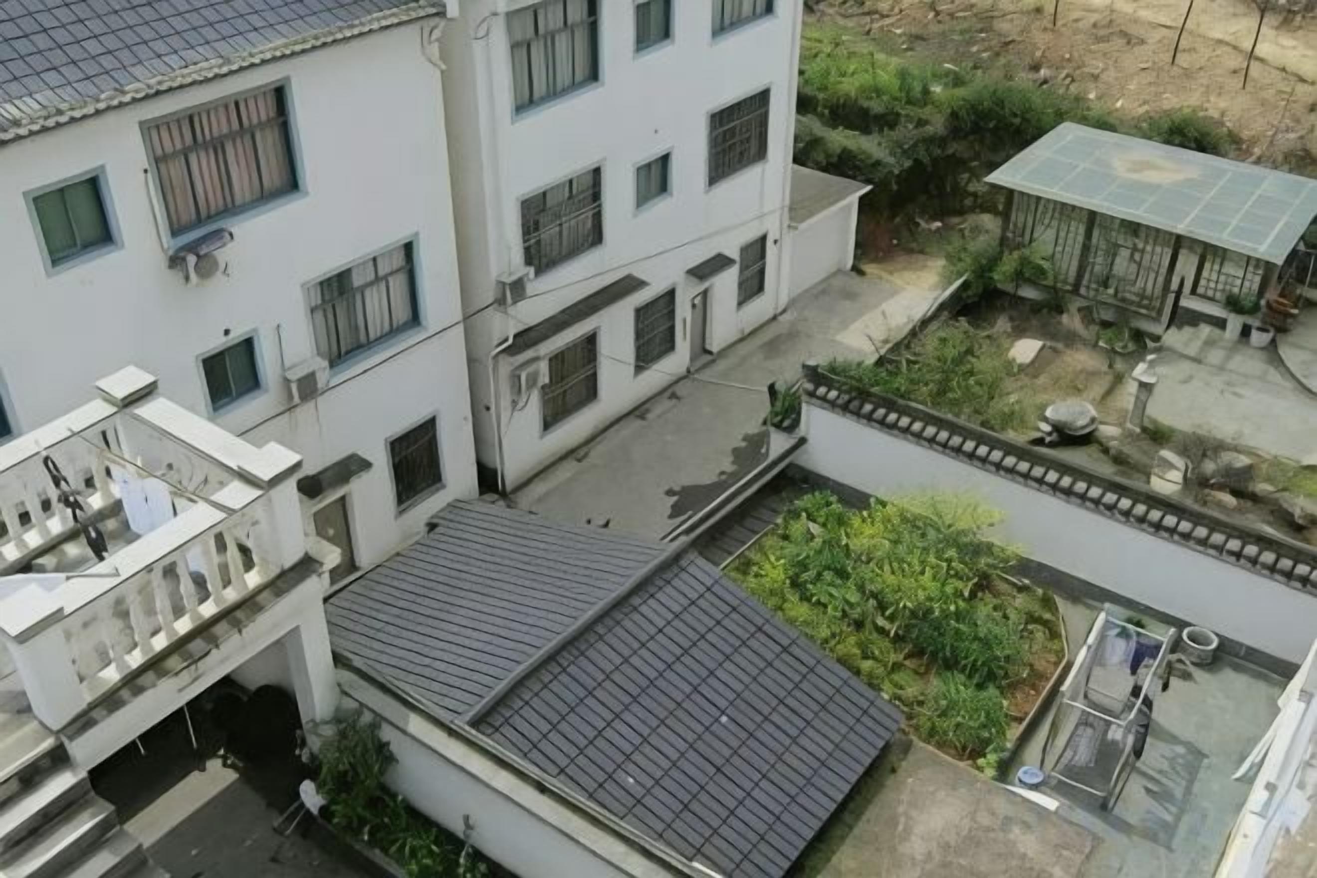 Un immeuble à plusieurs étages doté d’une cour intérieure, d’un espace extérieur abrité et d’un petit jardin.