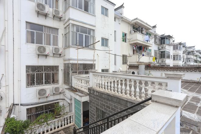 A multi-story residential building with balconies, air conditioning units, and a gated entrance.